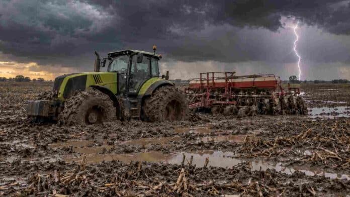 pronostico-lluvias-rafagas-14-provincias-ruralnet Tractor con sembradora encajado en un lote con rastrojo de maíz, barro y charcos durante una tormenta con relámpagos