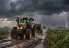 Pronóstico para viernes, sábado y domingo: las tormentas cambian de región y el norte llega a 36 °C Tractor amarillo avanza por un camino rural bajo una fuerte tormenta con lluvia, ráfagas y relámpagos