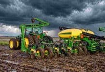 Girasol 2026/27: la siembra ya cubre el 26,6% del área prevista Tractor y sembradora John Deere trabajan sobre un lote con suelo húmedo bajo un cielo de tormenta con nubes oscuras.