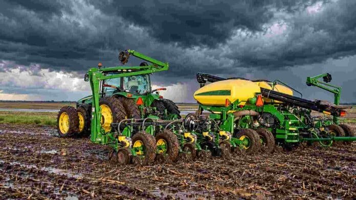 sembradora-john-deere-tormenta-ruralnet Tractor y sembradora John Deere trabajan sobre un lote con suelo húmedo bajo un cielo de tormenta con nubes oscuras.