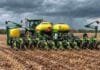 La soja recuperaría área y volvería al promedio de 5 años Tractor con sembradora de maíz trabajando sobre rastrojo y suelo húmedo bajo un cielo cubierto por nubes de lluvia.