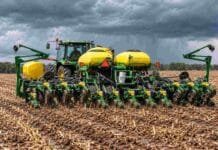 La soja recuperaría área y volvería al promedio de 5 años Tractor con sembradora de maíz trabajando sobre rastrojo y suelo húmedo bajo un cielo cubierto por nubes de lluvia.