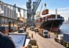 Argentina apunta a un superávit comercial récord de US$25.034 millones en 2026 Actividad exportadora en un puerto argentino con buque de carga, contenedores, camiones y terminales de granos, imagen ilustrativa del comercio exterior.