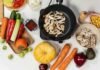 Día Mundial de los Fertilizantes: por qué la nutrición de los cultivos es decisiva para alimentar al mundo Vista cenital de una variedad de verduras frescas, hongos, zapallo, zanahorias, pimientos y palta sobre una mesa, junto a una sartén con vegetales salteados.