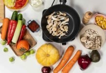 Día Mundial de los Fertilizantes: por qué la nutrición de los cultivos es decisiva para alimentar al mundo Vista cenital de una variedad de verduras frescas, hongos, zapallo, zanahorias, pimientos y palta sobre una mesa, junto a una sartén con vegetales salteados.