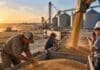 Sin retenciones, el agro podría sumar más de 850.000 empleos en 10 años, según FADA Trabajadores en una planta de acopio durante la carga de granos, con camiones, silos y una cosechadora al fondo, en una imagen ilustrativa del empleo agroindustrial argentino.