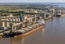 Agro argentino: un estudio revela que podría exportar US$ 122.000 millones si hubiera crecido como Brasil Vista aérea de una terminal agroexportadora con silos y buques cargueros sobre un río, ilustrando el comercio exterior agroindustrial argentino y su comparación con Brasil.