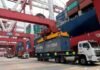 Argentina logró exportaciones récord y un superávit de US$ 2.976 millones Camiones transportan contenedores de carga en una terminal portuaria, mientras grúas de gran porte operan junto a un buque de carga en el marco del comercio internacional.
