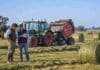 CREA identifica el tercer buen momento para invertir en el agro desde 2012 Productor y asesor técnico analizan datos en una tablet junto a un tractor Fendt 700 Vario con rotoenfardadora Massey Ferguson, rollos de alfalfa y rodeo Hereford en un campo argentino.