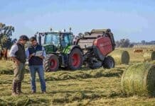 CREA identifica el tercer buen momento para invertir en el agro desde 2012 Productor y asesor técnico analizan datos en una tablet junto a un tractor Fendt 700 Vario con rotoenfardadora Massey Ferguson, rollos de alfalfa y rodeo Hereford en un campo argentino.