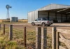 Invertir en el campo: una camioneta 4×4 cuesta 39% menos en kilos de novillo, pero construir un galpón es 33% más caro en trigo Camioneta 4x4 frente a un galpón agrícola, con alambrados, molino y tanque australiano en un establecimiento rural argentino, ilustrando los costos de inversión en el campo.