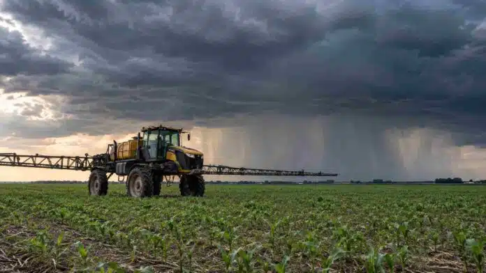 pronostico-9-11-octubre-pulverizadora-tormenta-ruralnet Pulverizadora autopropulsada detenida en un campo agrícola de la región pampeana, bajo un cielo de tormenta con lluvias intensas en el horizonte.