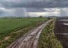 Pronóstico del 15 al 17 de octubre: lluvias y tiempo inestable en Buenos Aires, Córdoba y el Litoral Vista aérea de campos agrícolas y camino rural embarrado, con lluvias y un relámpago bajo un cielo de tormenta en la región pampeana argentina.