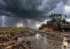 Pronóstico del 16 al 18 de octubre: llegan lluvias y tormentas el viernes y mejora el tiempo hacia el domingo Tractor trabajando sobre un camino rural embarrado bajo una tormenta con lluvias intensas y relámpagos en un campo
