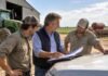 RENATRE: aprueban un plan de pago de deudas con hasta 12 cuotas y quitas del 50% en intereses Productor agropecuario revisa documentación junto a dos trabajadores rurales en un establecimiento agrícola argentino, con un tractor y maquinaria de siembra de fondo.