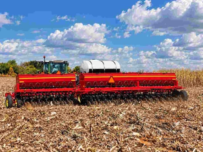 sembradora-girasol-siembra-directa-campo-argentino-ruralnet Sembradora Sunflower de gran porte trabajando sobre rastrojos de maíz en un campo agrícola, bajo un cielo azul con grandes nubes blancas.