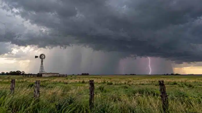 Tormenta fuerte sobre un campo rural con cortina de lluvia, relámpagos y cielo oscuro cargado.