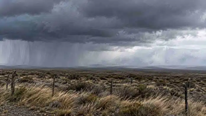 Tormenta intensa sobre un paisaje rural de la Patagonia, con nubes oscuras, cortinas de lluvia y pastizales sacudidos por el viento.
