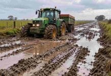 “Deterioro alarmante”: el reclamo del campo bonaerense por el uso de fondos viales en obras contra inundaciones Tractor avanzando con dificultad por un camino rural con barro y agua en la provincia de Buenos Aires.