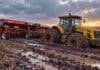 Las lluvias frenaron la cosecha de trigo y la siembra de soja en Santa Fe Tractor Pauny y sembradora Apache encajados en el barro de un campo en barbecho, con suelo saturado de humedad, huellas profundas y charcos de agua.