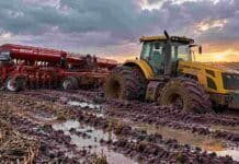Las lluvias frenaron la cosecha de trigo y la siembra de soja en Santa Fe Tractor Pauny y sembradora Apache encajados en el barro de un campo en barbecho, con suelo saturado de humedad, huellas profundas y charcos de agua.