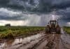 Tormentas fuertes y lluvias persistentes: siete provincias bajo alerta meteorológica Tractor Zanello con cabina y neumáticos cubiertos de barro avanza por un camino rural anegado mientras una fuerte tormenta con lluvia intensa y relámpagos se desarrolla sobre el campo.